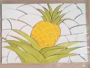 Handmade ceramic mosaic of a yellow pineapple on white porcelain.